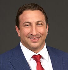 Headshot of a professional in a blue suit and red tie, featured at Scale Community Events.