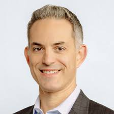 Man smiling in a business suit at Scale Community Events, showcasing professional networking opportunities.
